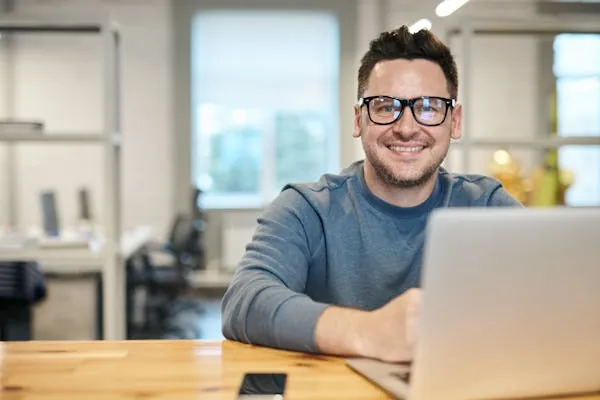 A smiling staff member working at a laptop